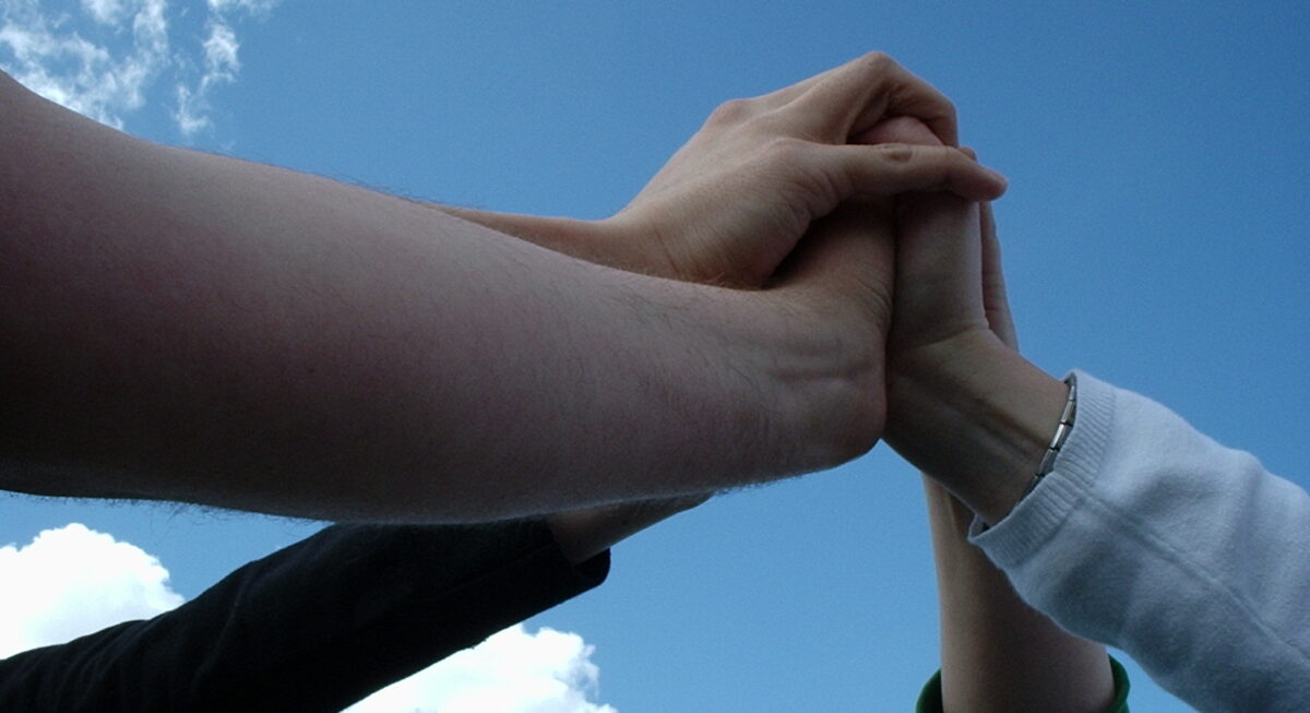 A team reaching up to touch hands in a star shape