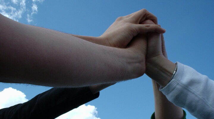 A team reaching up to touch hands in a star shape